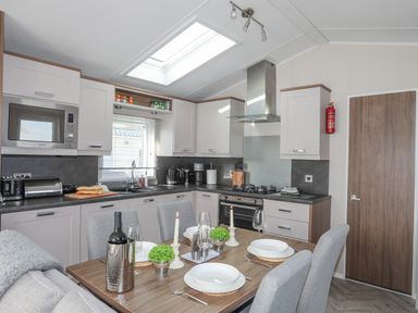 A kitchen with a dining table set for four and cooking appliances at 97 Crugan in Llanbedrog