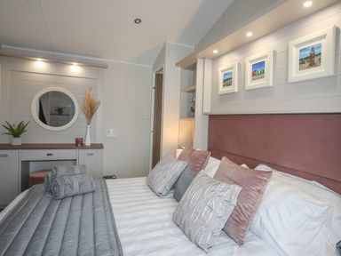 A bedroom with a bed featuring multiple pillows and folded towels at 97 Crugan in Llanbedrog