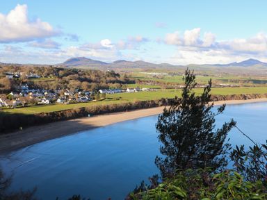 A coastal village with houses near a beach and hills in the background at 97 Crugan in Llanbedrog