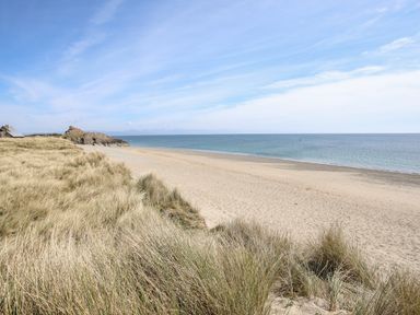 A sandy beach with sea and grass dunes at 97 Crugan in Llanbedrog