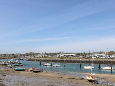 A harbor with boats on water and some boats grounded on mud at 97 Crugan in Llanbedrog