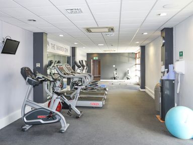 An exercise room with stationary bikes treadmills rowing machines and a blue exercise ball at 97 Crugan in Llanbedrog