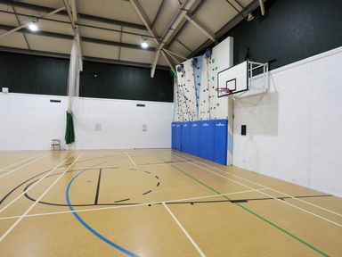 An indoor sports hall with a basketball hoop and climbing wall at 97 Crugan in Llanbedrog