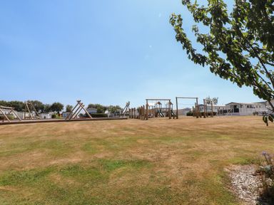 An outdoor playground with swings and climbing frame at 97 Crugan Llanbedrog