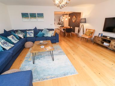 A living room with a blue sectional sofa and wooden coffee table next to a dining area at Tregenna House in St Ives