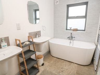 A bathroom with two sinks a freestanding bathtub and a shelving unit at Tregenna House St Ives
