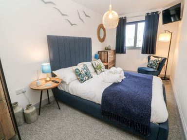 A bedroom with a blue upholstered bed wooden side table and chest of drawers at Tregenna House in St Ives