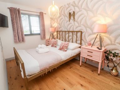 A bedroom with a bed a wooden floor two pink bedside tables and lamps at Tregenna House in St Ives