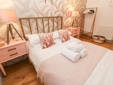 A bedroom with a double bed pink bedside tables lamps and a clothes rack at Tregenna House in St Ives