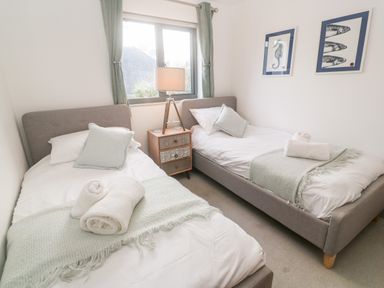 A bedroom with two single beds a lamp on a nightstand and ocean themed pictures on the wall at Tregenna House in St Ives