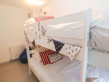 A bedroom with white bunk beds decorated with nautical-themed bunting and pillows at Tregenna House in St Ives