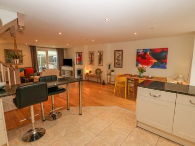 An open living and dining area with bar stools and kitchen cabinets at Barn End 9 Stad Clynnog in Newborough