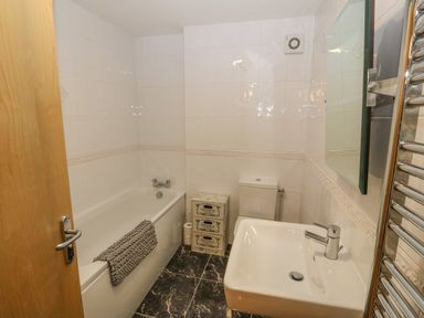A bathroom with a bathtub a toilet a sink and a towel radiator at Barn End 9 Stad Clynnog in Newborough