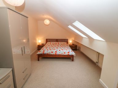A bedroom with a double bed between two bedside tables and a wardrobe at Barn End 9 Stad Clynnog in Newborough