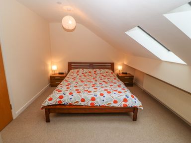 A bedroom with a double bed and two bedside tables with lamps under skylights at Barn End 9 Stad Clynnog in Newborough