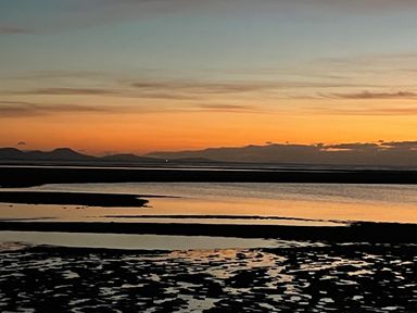 A beach landscape with water and sand at sunset at Barn End 9 Stad Clynnog in Newborough