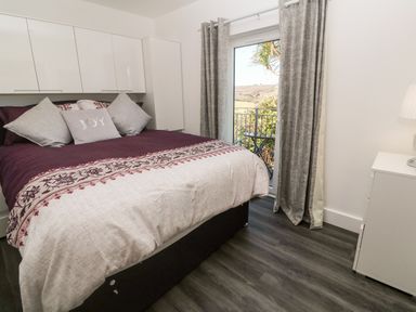 A bedroom with a bed pillows and a window with curtains showing an outdoor view at Perran Pearl A in Perranporth