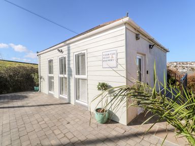Exterior view of a holiday apartment building with paved patio and potted plants at Perran Pearl A in Perranporth