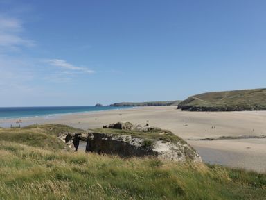 A sandy beach with cliffs and grassy areas near the ocean at Perran Pearl B in Perranporth