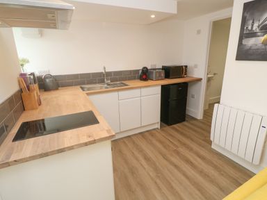 A kitchen with wooden countertops a sink stovetop toaster microwave and small refrigerator at Perran Pearl B in Perranporth