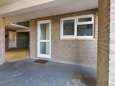 An outdoor area with a white door and window on a brick wall and a doormat on the floor at Beach Side in West Bay