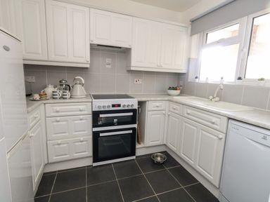 A kitchen with white cabinets a stove a sink a dishwasher and a bowl of fruit on the counter at Beach Side in West Bay