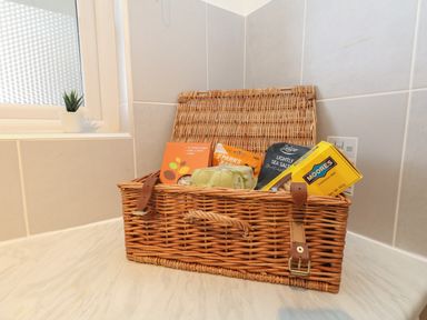 A wicker basket with snacks and small plant on a tiled countertop at Beach Side in West Bay