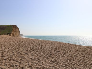 A pebble beach with cliffs on the left and the sea on the right at Beach Side in West Bay