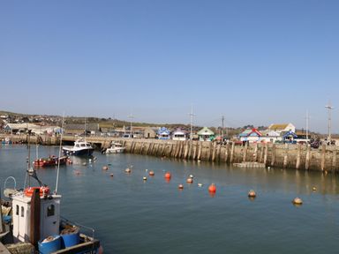 A harbor with boats docked and colorful huts along the pier at Beach Side in West Bay
