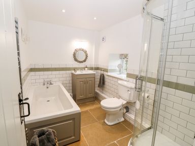 A bathroom with a bathtub sink with cabinet toilet and shower at Rhytty Bach in Ty Croes near Rhosneigr