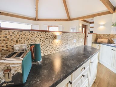 A kitchen countertop with a toaster and kettle near a tiled backsplash at Oversands Cottage in Grange-Over-Sands