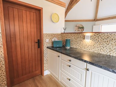 A kitchen countertop with a toaster and kettle next to a wooden door at Oversands Cottage in Grange-Over-Sands