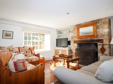 A living room with wooden furniture a stone fireplace and a television at 1 The Lane in Chipping Norton