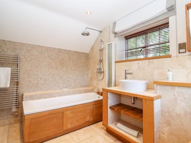 A bathroom with a bathtub shower combination sink with mirror and window with blinds at 1 The Lane in Chipping Norton