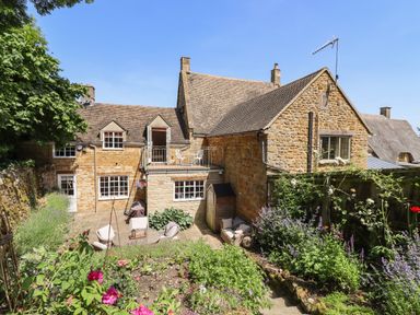 A stone house with a garden patio and outdoor chairs at 1 The Lane in Chipping Norton