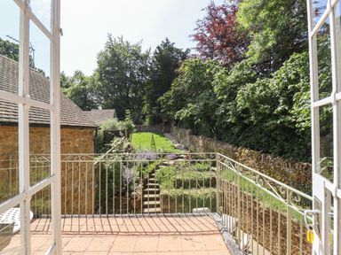 A balcony overlooking a garden with stone steps shrubs and trees at 1 The Lane in Chipping Norton