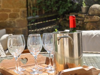 A set of wine glasses and a bottle in a metal ice bucket on a wooden tray outdoors at 1 The Lane in Chipping Norton