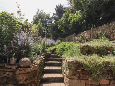 Stone steps leading up a garden with stone retaining walls and various plants and flowers at 1 The Lane in Chipping Norton