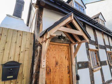 Front entrance of a timber framed house with a wooden door and a black mailbox at 18 Church Street in Llangollen
