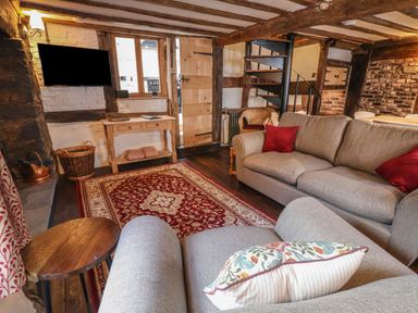 A living room with sofas red pillows wooden table and a spiral staircase at 18 Church Street in Llangollen