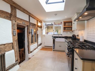 A kitchen with a stove sink cupboards and wooden beams at 18 Church Street in Llangollen