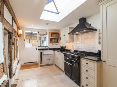A kitchen with cream cabinets black countertops a black stove and a skylight at 18 Church Street in Llangollen