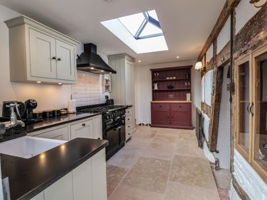 A kitchen with cream cabinets black countertop black stove red wooden cabinet and a skylight at 18 Church Street in Llangollen