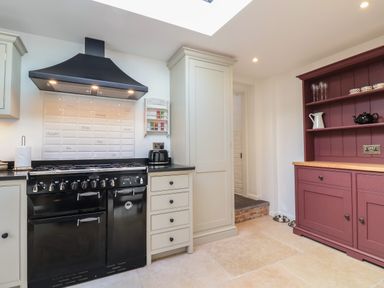 A kitchen with a black stove and hood beige cabinets and a maroon wooden cabinet at 18 Church Street in Llangollen