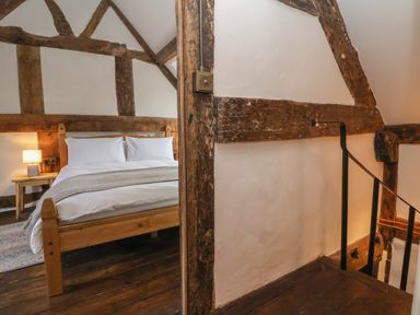 A bedroom with wooden beams a wooden bed and a bedside table with a lamp at 18 Church Street in Llangollen