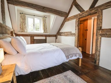 A bedroom with a bed wooden beams on walls wooden floor and window with curtains at 18 Church Street in Llangollen