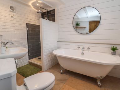 A bathroom with a toilet sink shower bathtub and round mirror at 18 Church Street in Llangollen