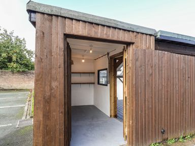 An open wooden shed with shelves inside and a concrete floor at 18 Church Street in Llangollen