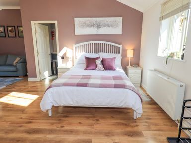 A bedroom with a bed and lamp at The Garden Suite at Fiddler Hall Barn, Newby Bridge