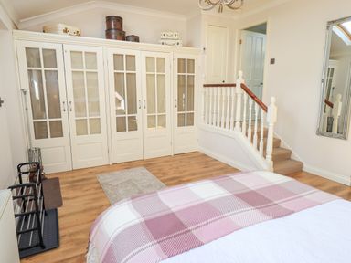 A bedroom with a wardrobe and stairs at The Garden Suite at Fiddler Hall Barn Newby Bridge